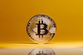 a bit coin sitting on top of a reflective surface