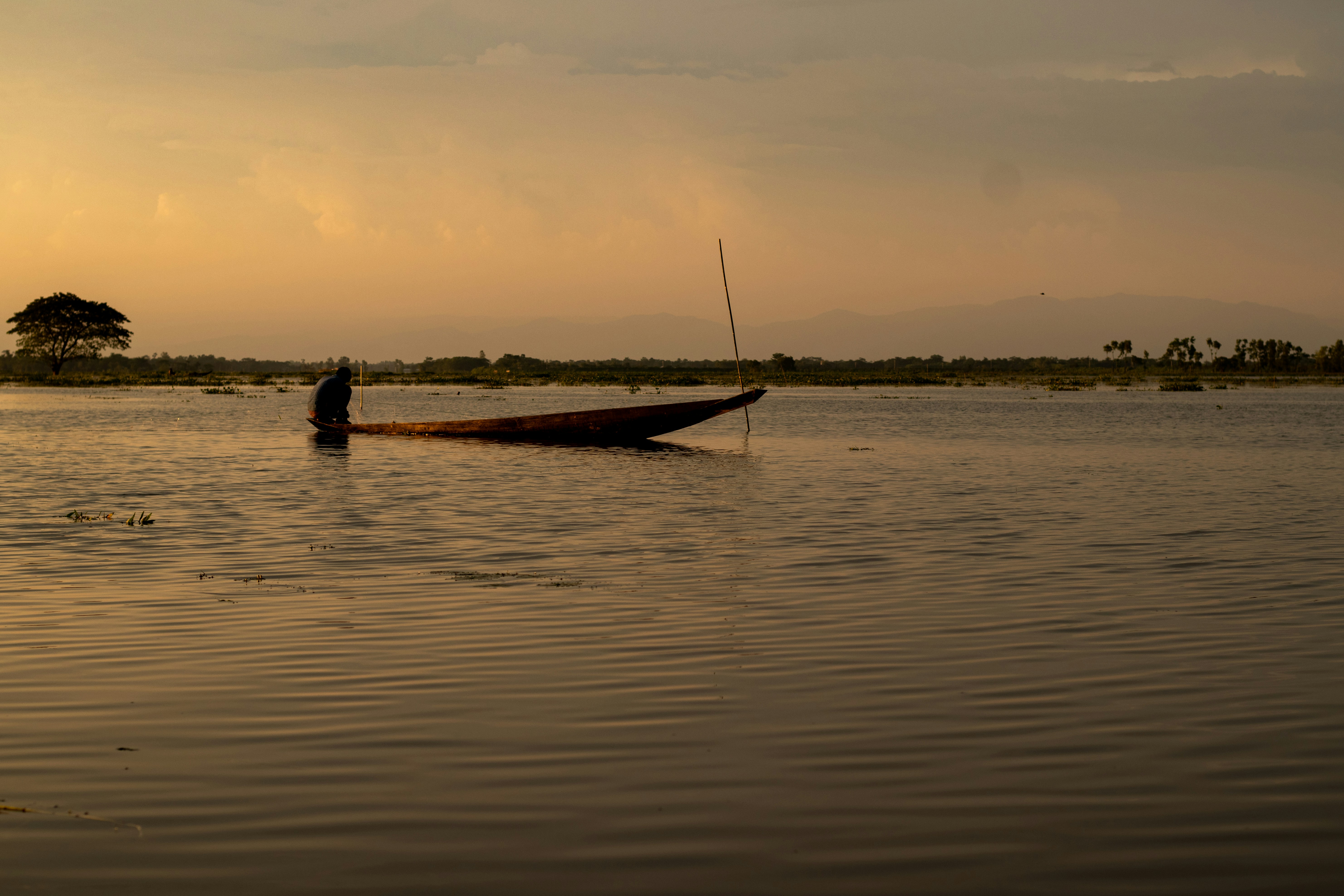 A boatman fishing with the net on a large water field