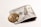 A stack of US hundred-dollar bills is folded and placed on a light background. Beside it, there is a shiny gold coin featuring the Bitcoin symbol. The image juxtaposes traditional currency with cryptocurrency.