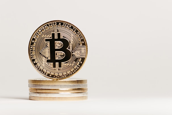 A close-up view of a stack of shiny coins with a focus on a Bitcoin, showcasing intricate engravings and the iconic Bitcoin symbol at the center.