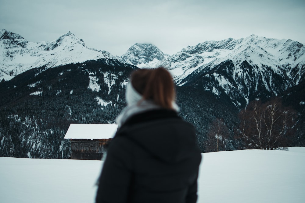 a woman standing in the snow looking at mountains