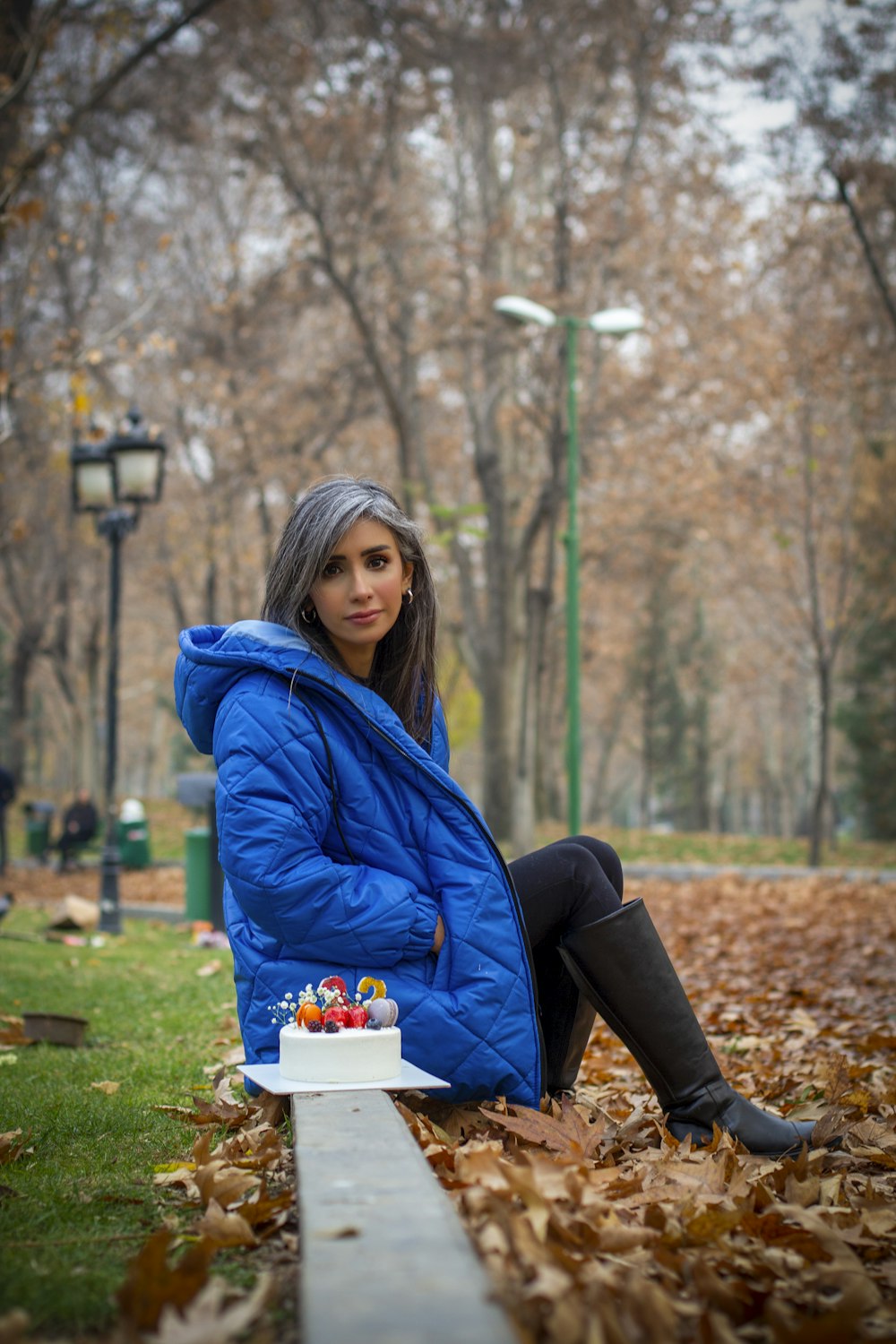 a woman sitting on the ground with a cake