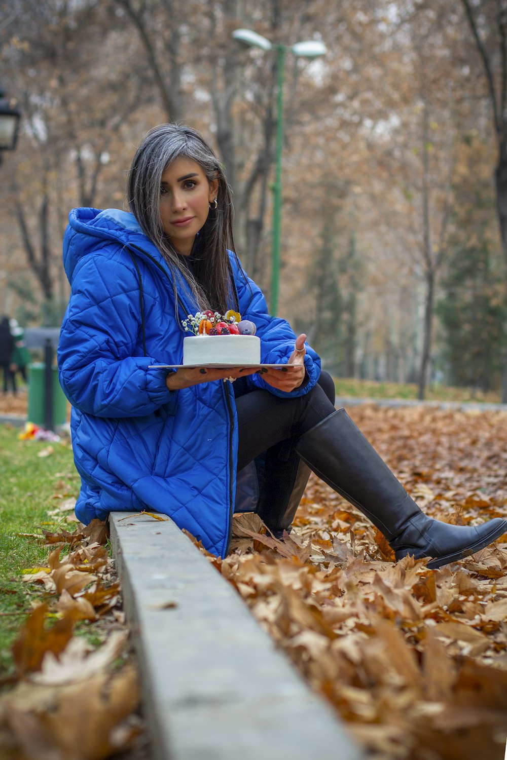 a woman sitting on a bench holding a cake