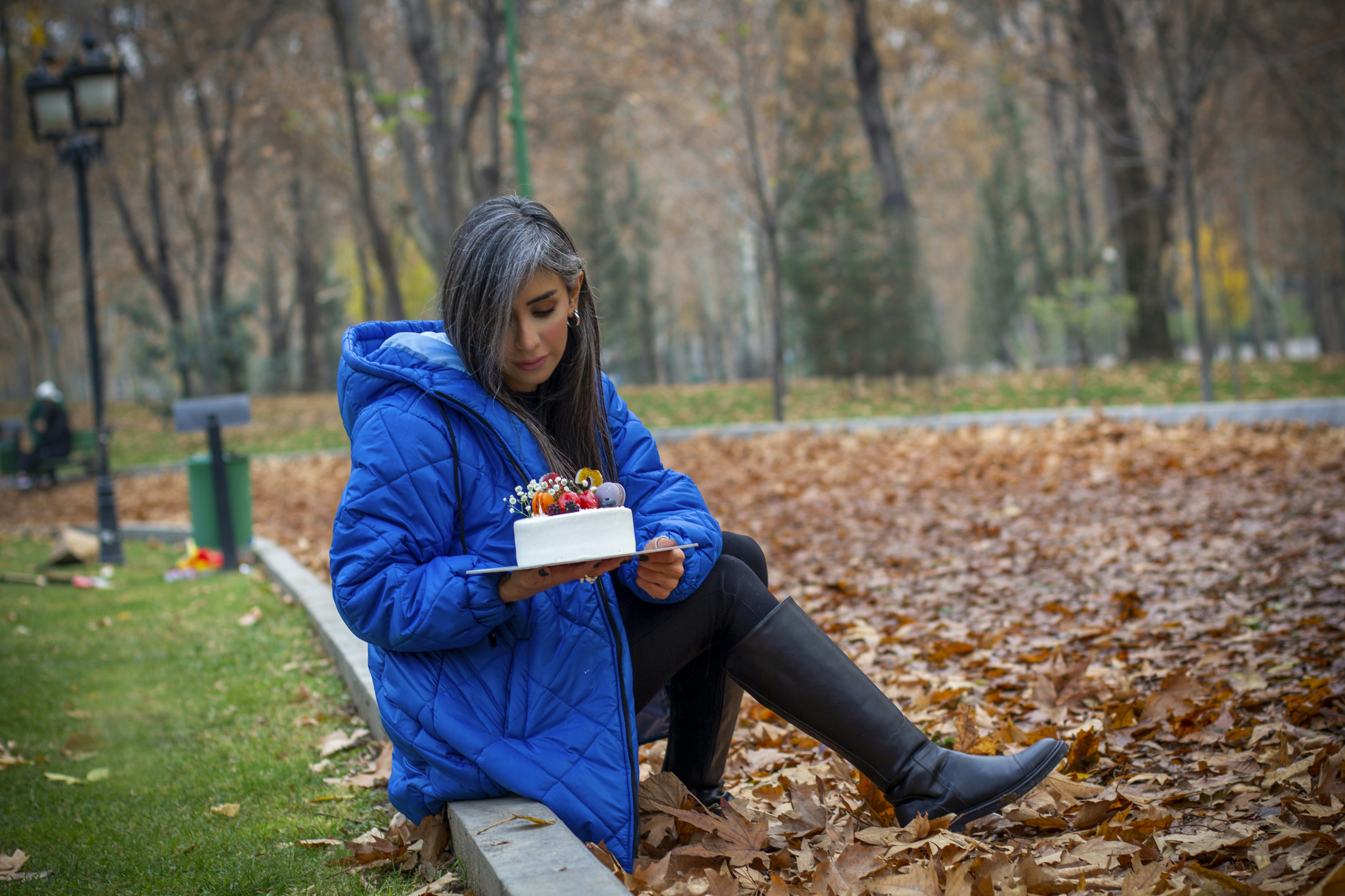 a woman sitting on a bench holding a cake