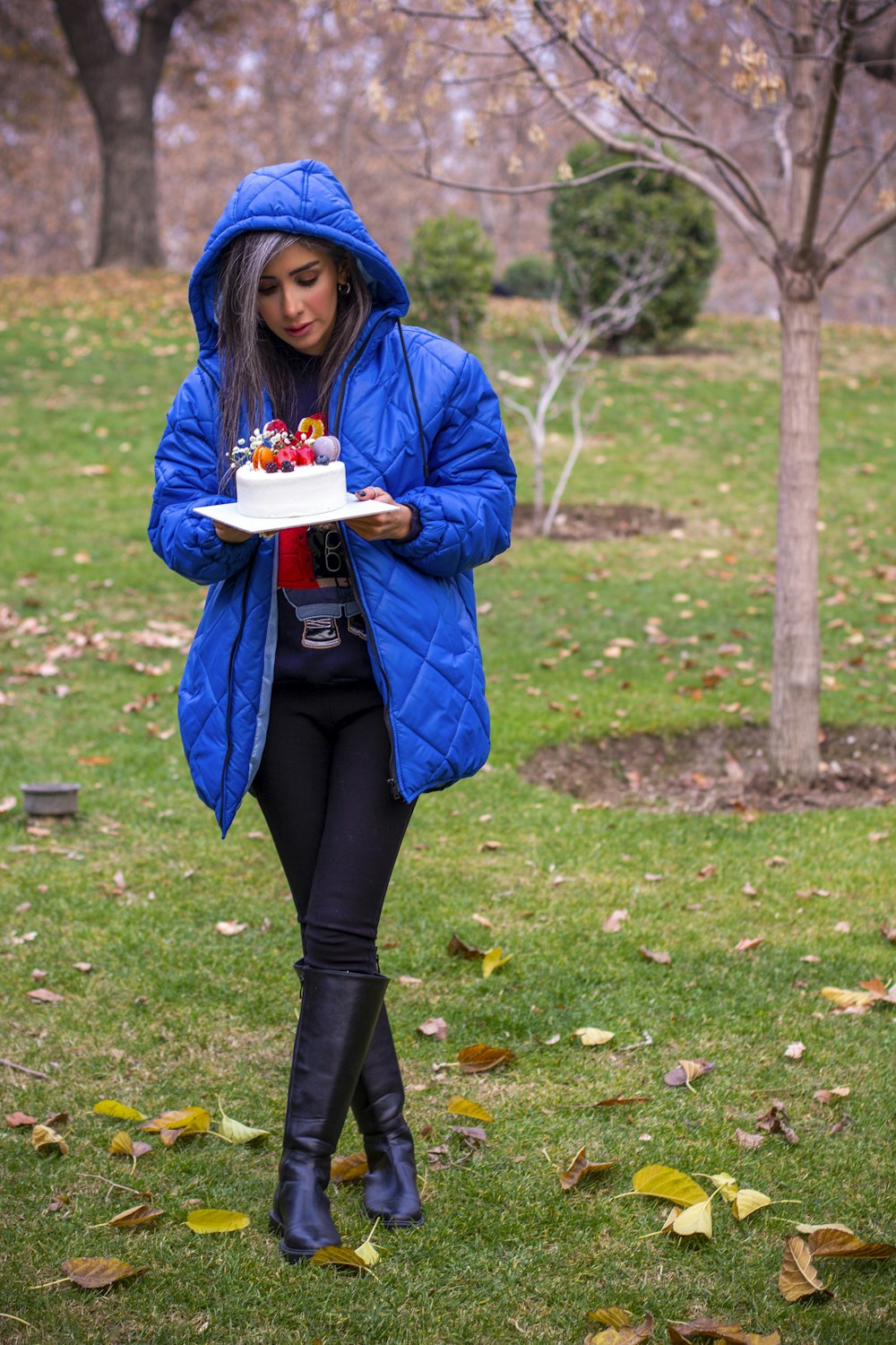 a woman in a blue jacket carrying a cake