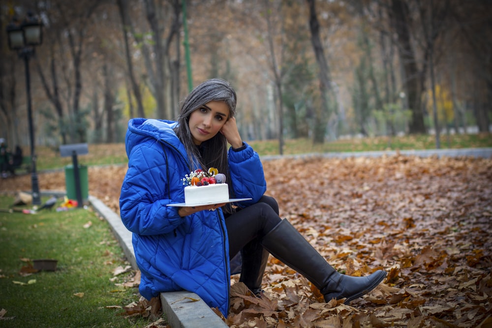 a woman sitting on a bench holding a cake