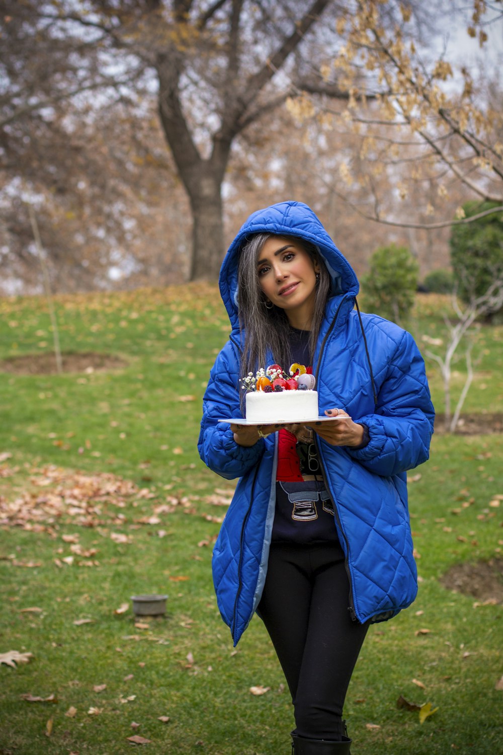 a woman in a blue jacket holding a cake