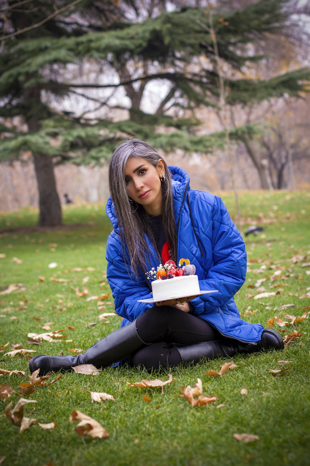 a woman sitting in the grass holding a cake