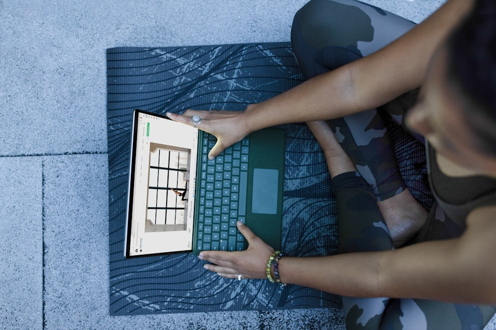 a woman using a laptop computer on a mat