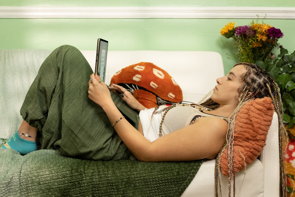 a woman laying on a couch with a laptop