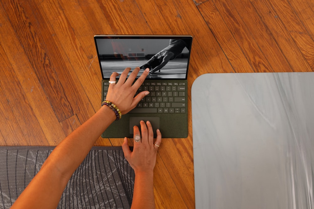 a woman using a laptop computer on a wooden floor