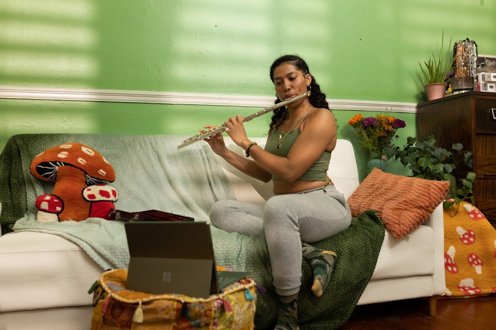 a woman sitting on a couch playing a flute