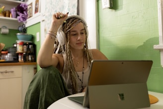 a woman with dreadlocks sitting in front of a laptop computer