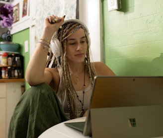 a woman with dreadlocks sitting in front of a laptop computer