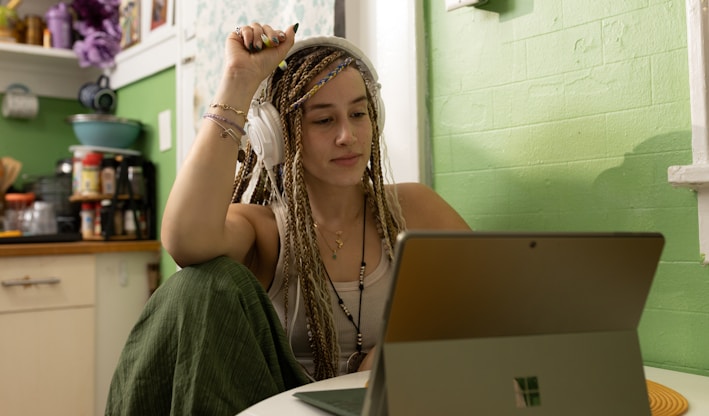 a woman with dreadlocks sitting in front of a laptop computer