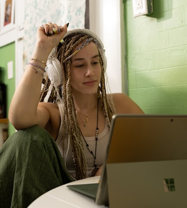 a woman with dreadlocks sitting in front of a laptop computer