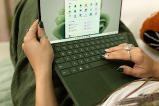 A friendly person typing on a laptop with coral accents in the background.