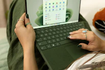 A small business owner happily using a laptop with blue, white, and black themed interface.