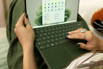 A small business owner happily using a laptop with blue, white, and black themed interface.