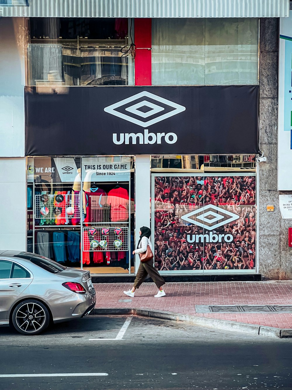 a man walking across a street in front of a store