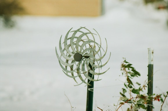 A close-up of a colorful metal wind spinner gently turning in a sunny Greek garden.