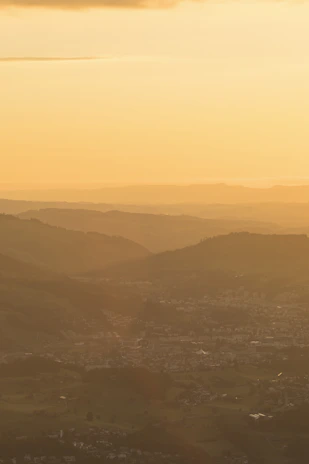 Sunset view over the rolling hills surrounding Döğer Kasabası, casting warm golden light.