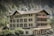 A multi-story traditional building with white walls and brown shutters labeled 'Hotel Staubbach' stands against a backdrop of steep rocky cliffs and lush green trees. Several balconies adorned with flags offer views of the picturesque surroundings.