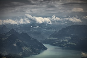 A panoramic view of a winding river cutting through a deep valley with towering mountains