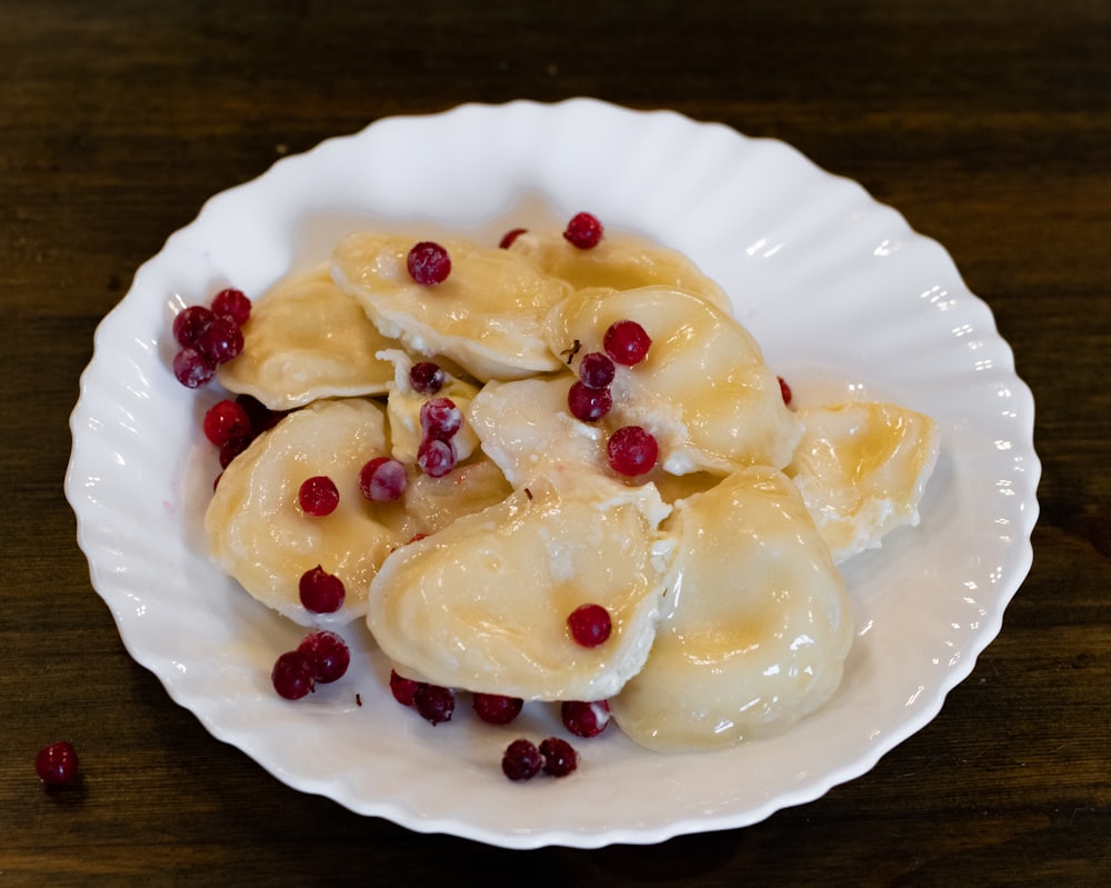 a white plate topped with dumplings covered in cheese and cranberries