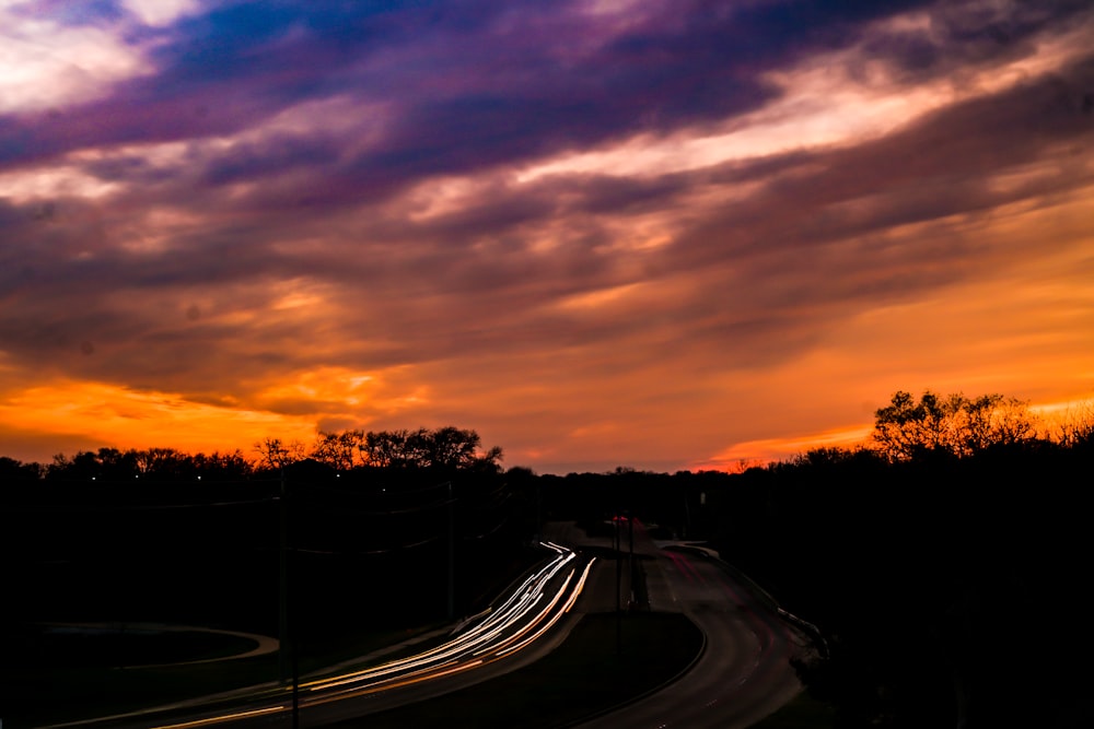 a sunset view of a highway with cars driving on it