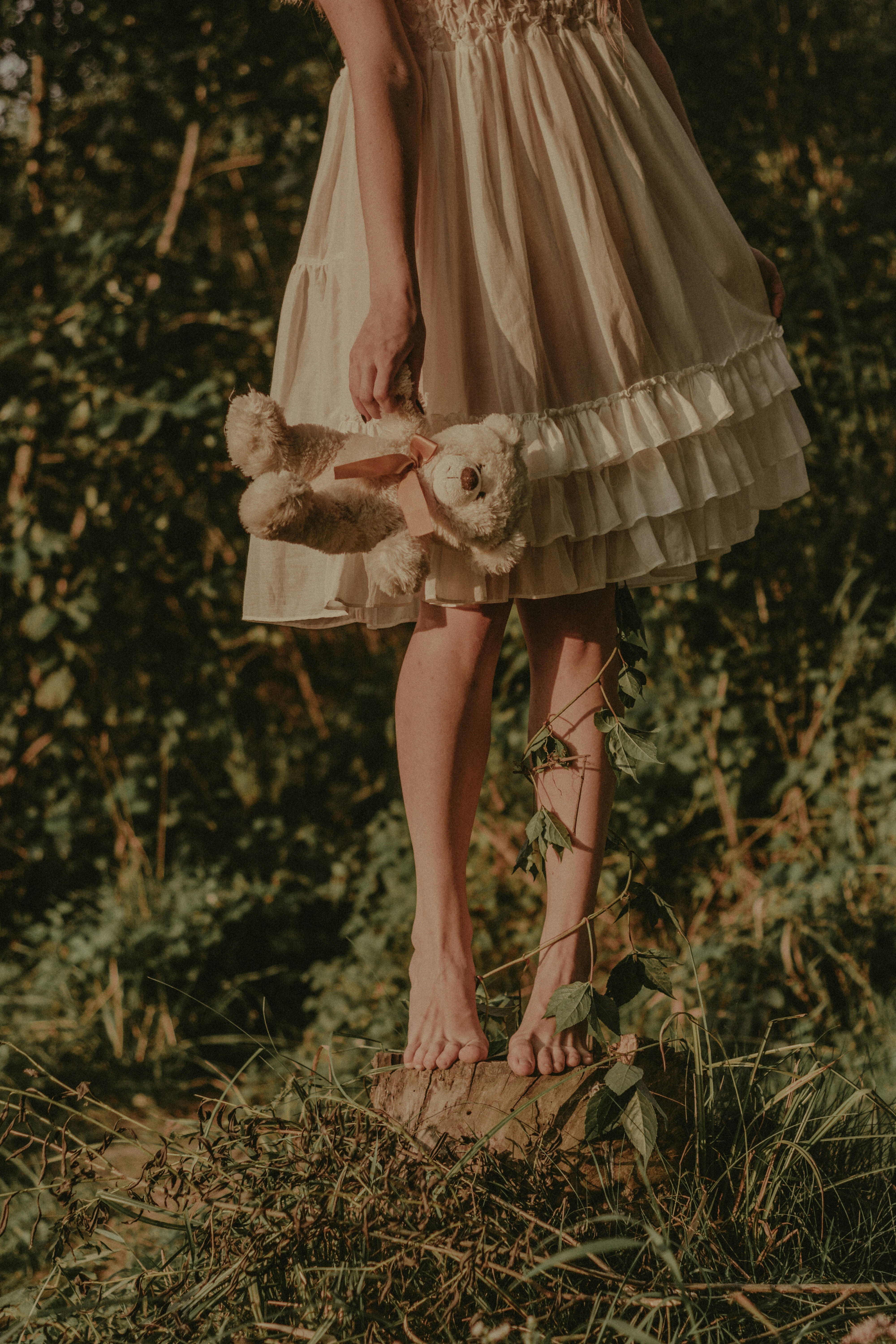 a woman in a dress holding a teddy bear