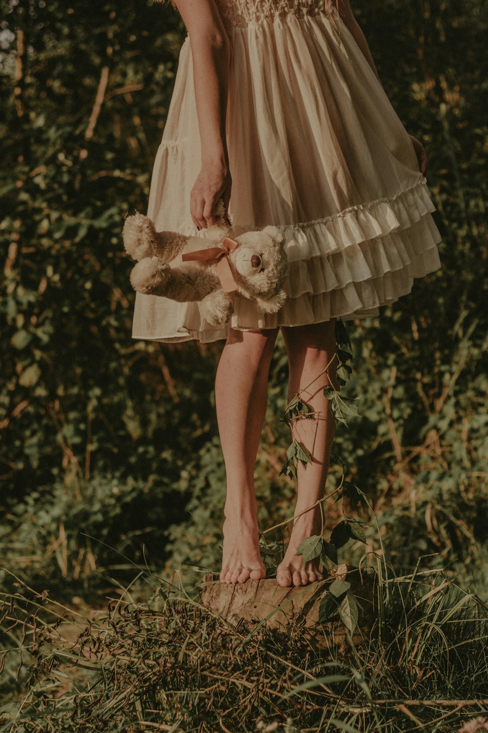 a woman in a dress holding a teddy bear