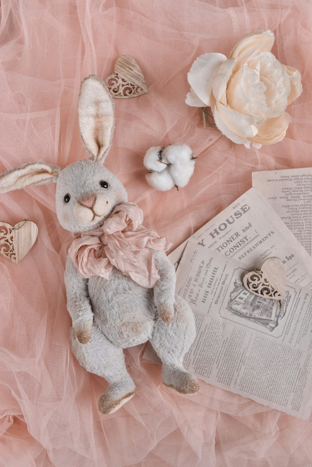 a stuffed rabbit sitting on top of a pink sheet