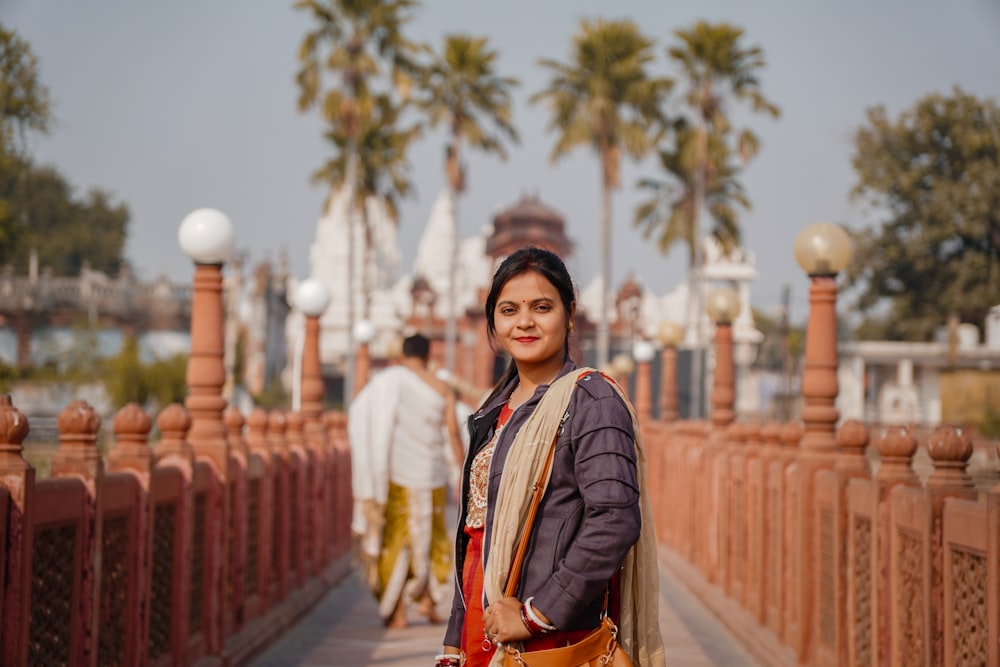 a woman standing on a bridge with palm trees in the background