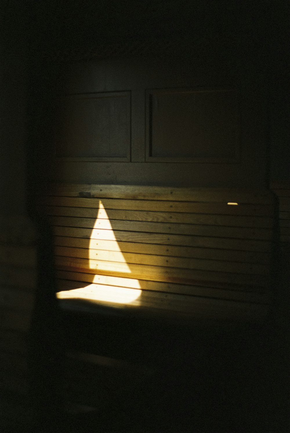 a light shines on a bench in a dark room