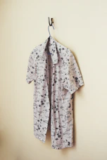 A stylish ethnic shirt in charcoal with subtle peacock feather patterns, displayed on a wooden hanger.