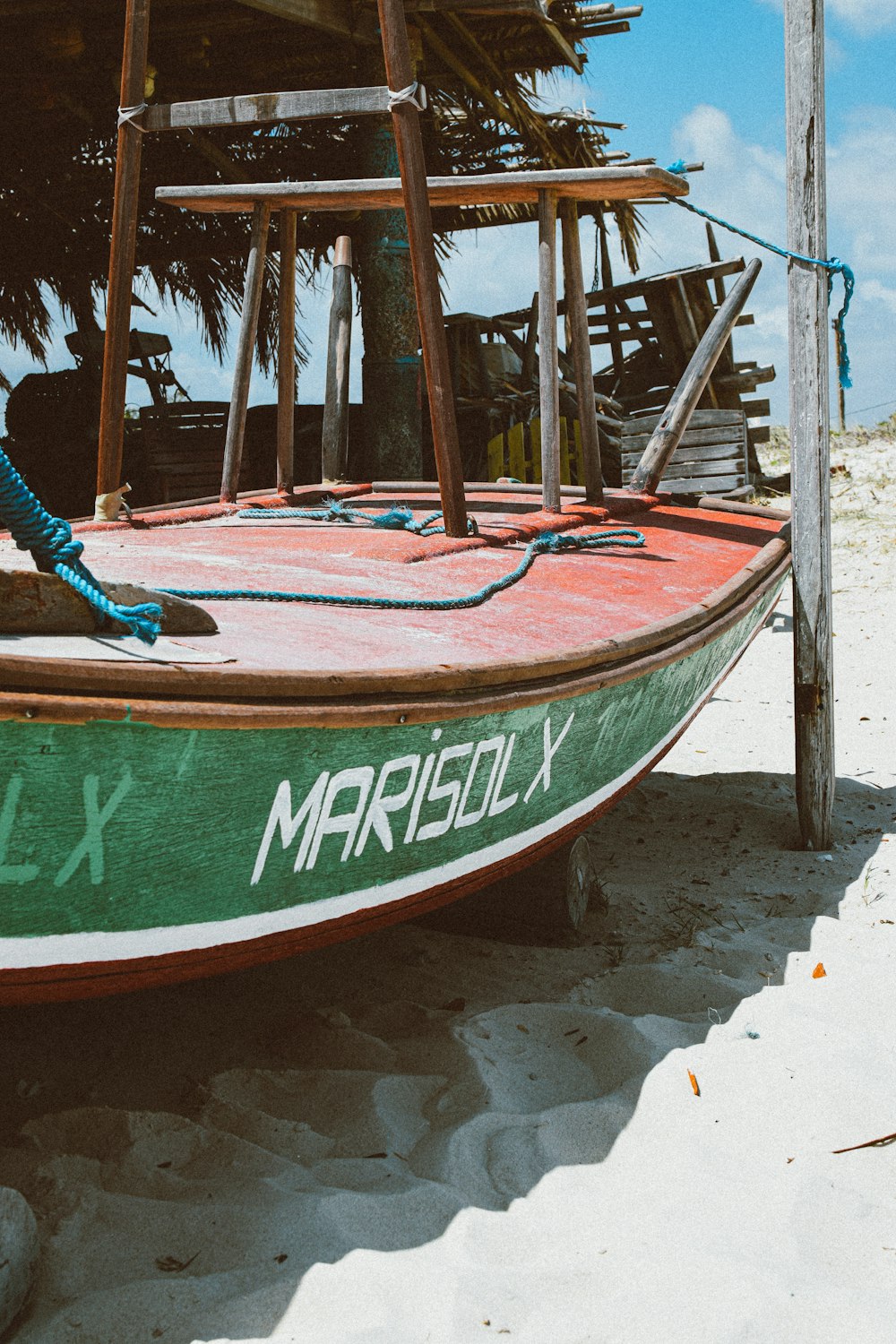a green and white boat sitting on top of a sandy beach