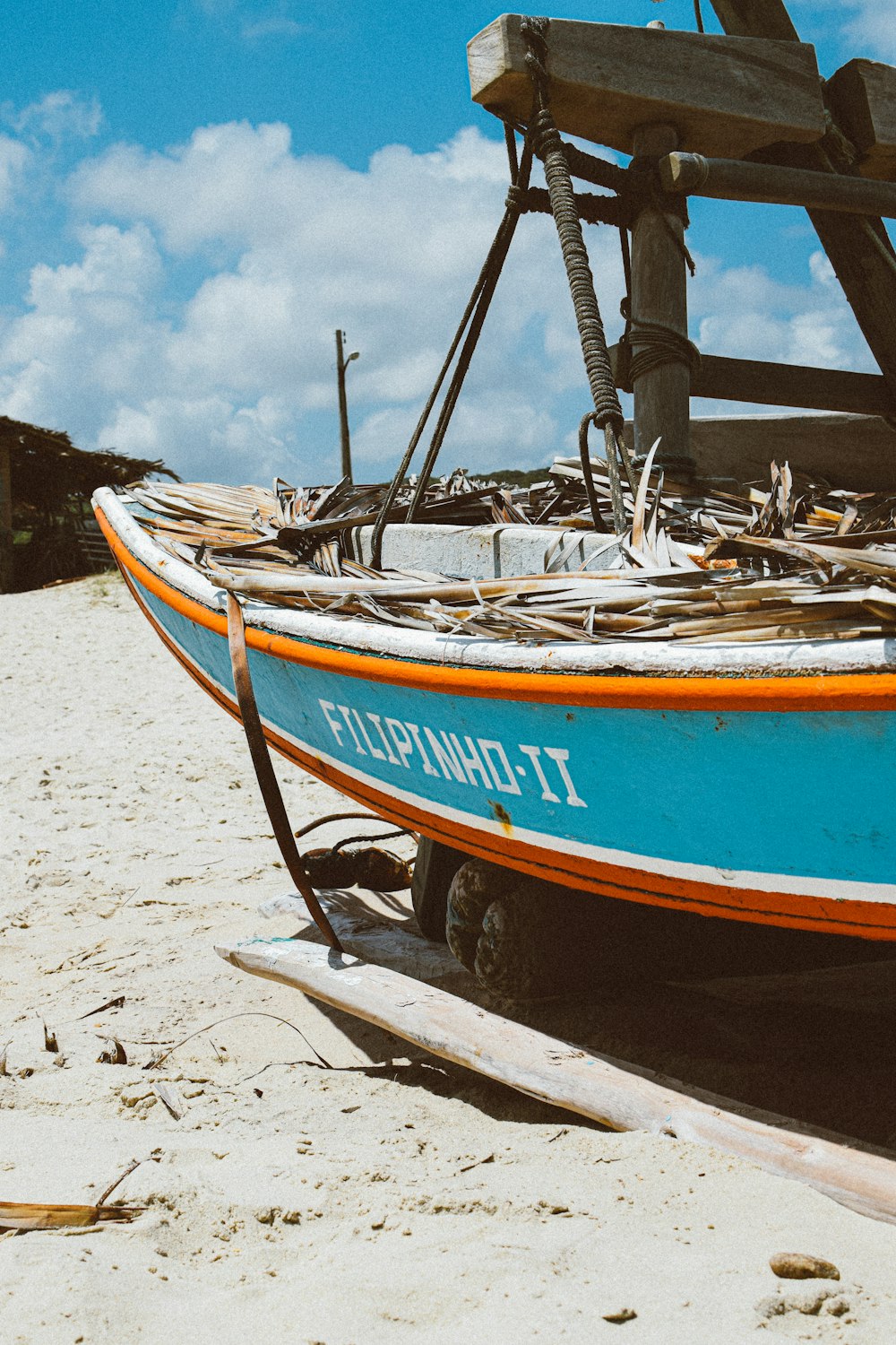 a blue and orange boat sitting on top of a sandy beach