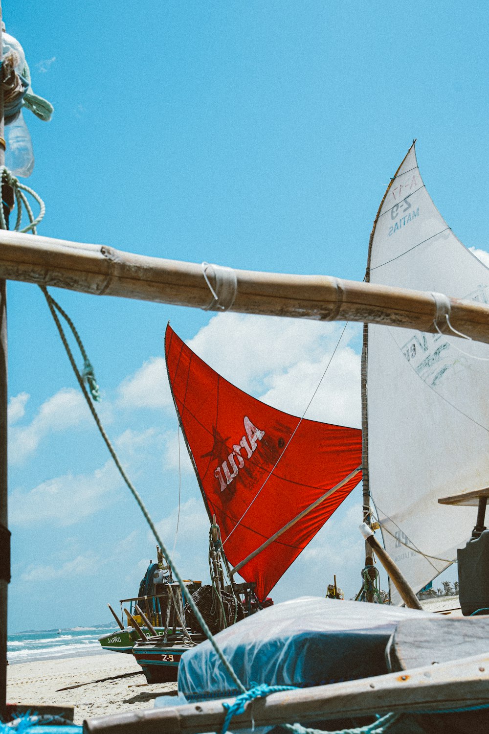 a red sail boat sitting on top of a sandy beach