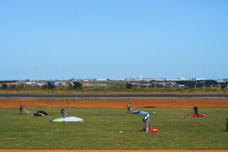 A panoramic shot of a busy dropzone with planes lined up and parachutes laid out on the grass.
