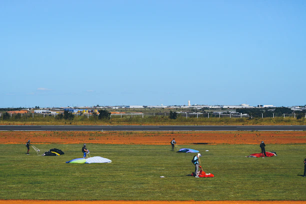 A panoramic shot of a busy dropzone with planes lined up and parachutes laid out on the grass.