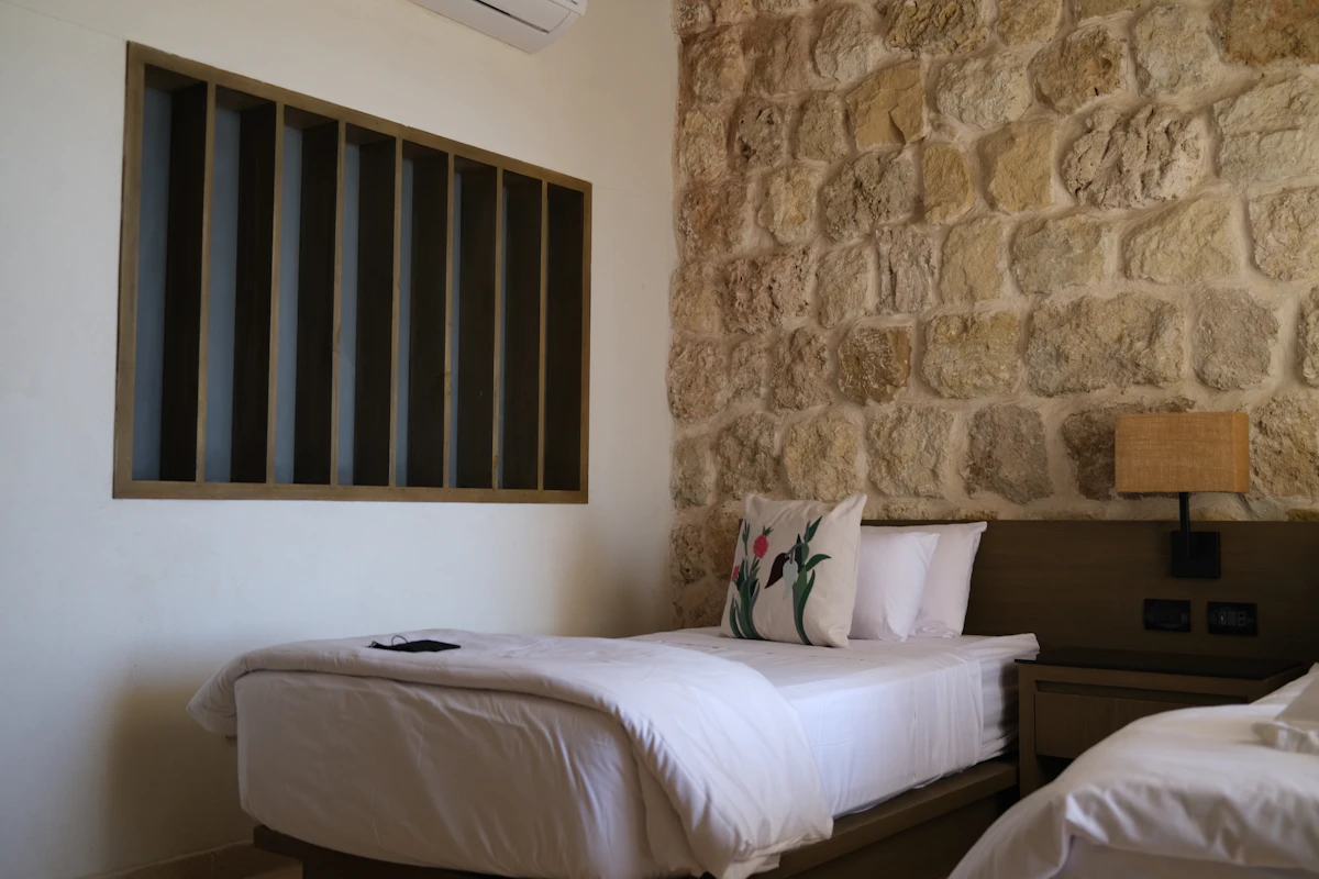 Dormitorio con pared de piedra y cama de ropa blanca