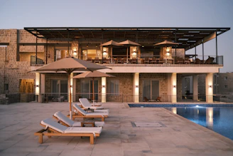 two lounge chairs and an umbrella near a swimming pool