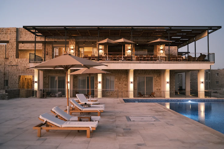 two lounge chairs and an umbrella near a swimming pool