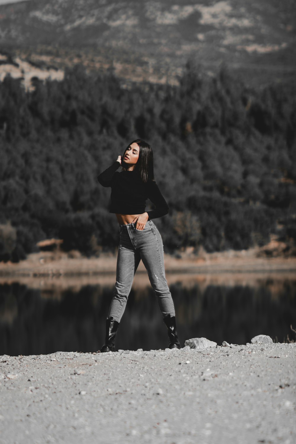 a woman standing on top of a beach next to a lake