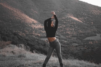 a woman standing on top of a lush green hillside