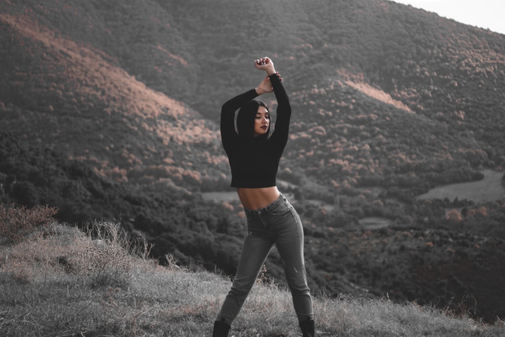 a woman standing on top of a lush green hillside