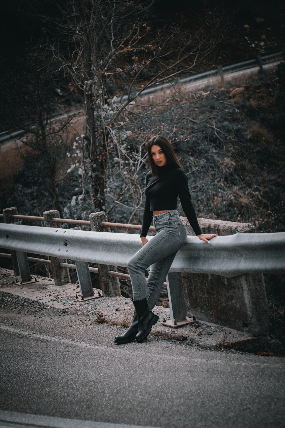 a woman standing on a bridge with her legs crossed