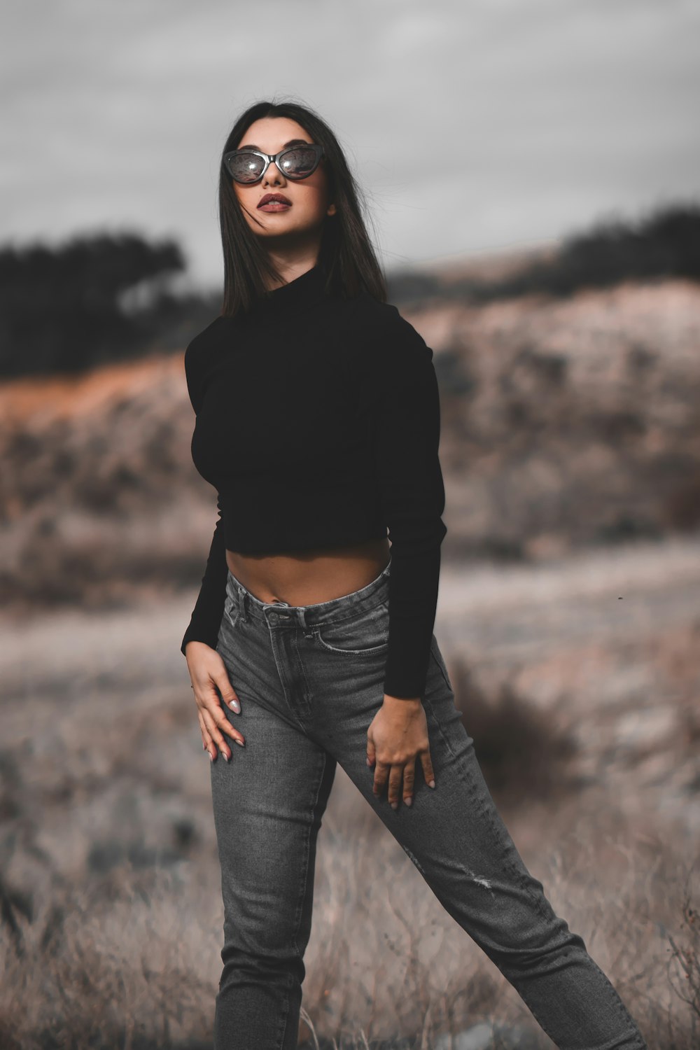 a woman standing in a field with her hands on her hips