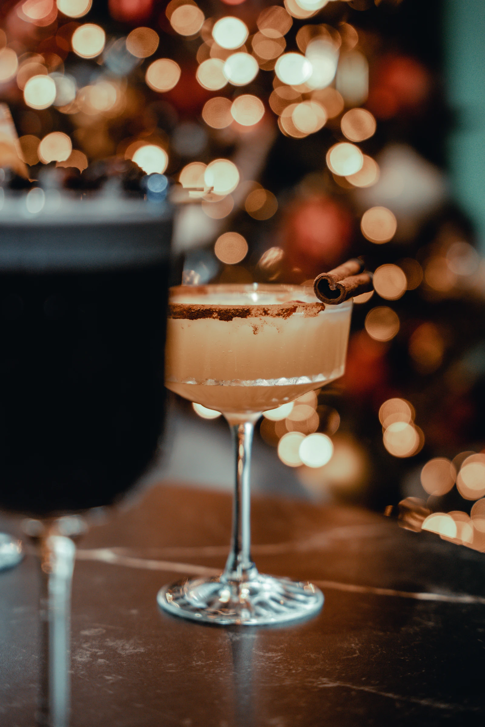 Two drinks sitting on a table next to a Christmas tree